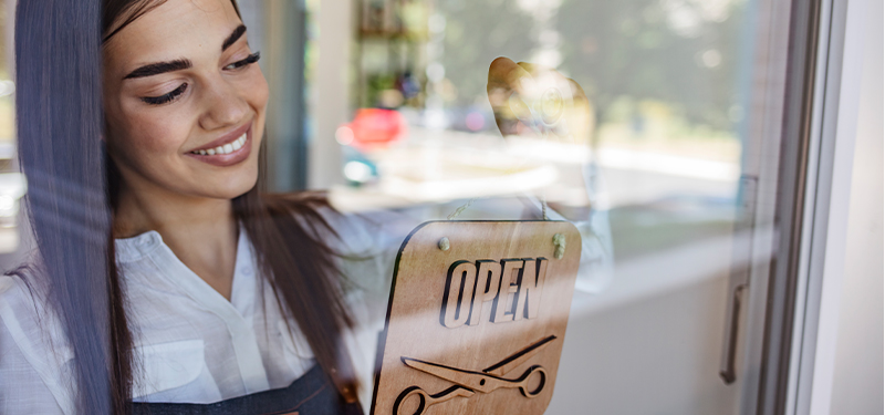 A woman hanging an open sign in a window