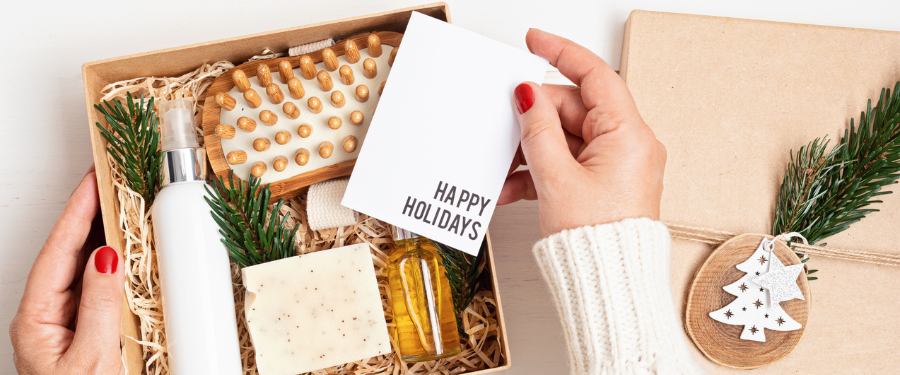 A woman holding a happy holidays card and gift box with beauty products