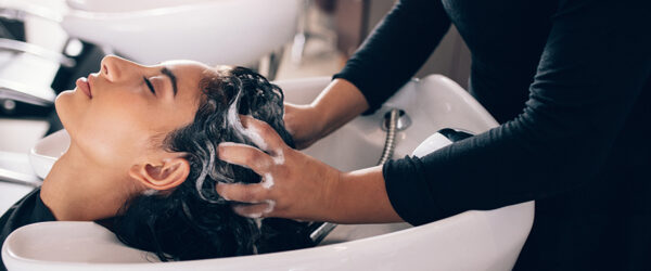 salon trends - stylist washing a clients hair at shampoo bowl