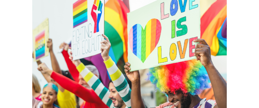 People with signs and rainbow flags at a pride parade