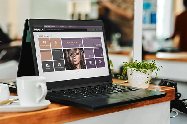 Meevo on a laptop near a hair stylist station