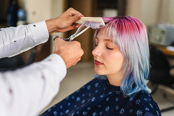 Hairstylist cutting client bangs in chair