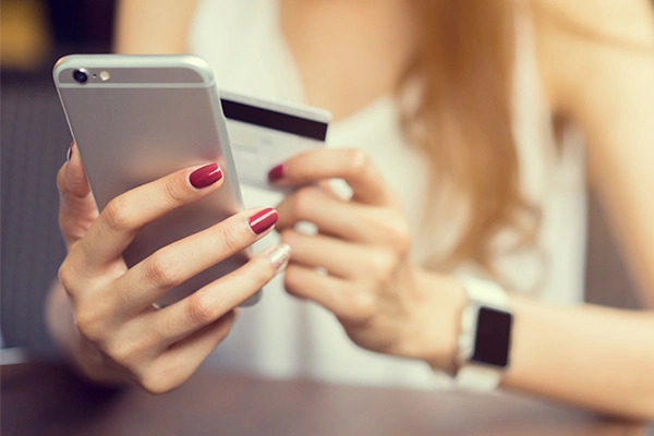 Female with credit card paying on mobile phone